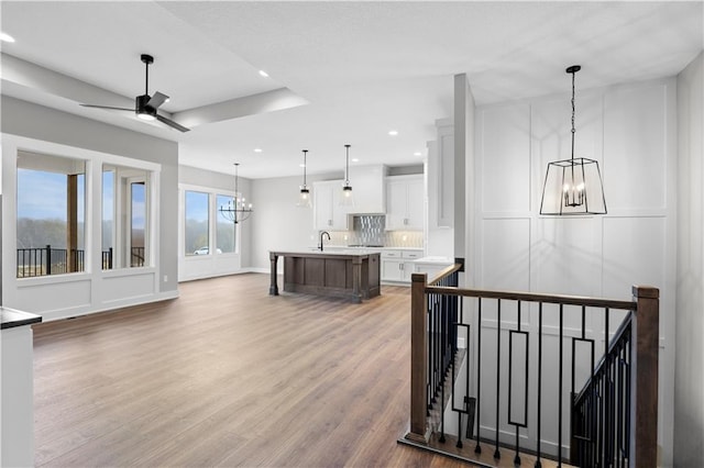 living room featuring hardwood / wood-style flooring, ceiling fan with notable chandelier, and sink