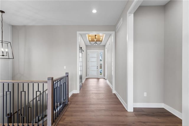 hall with dark hardwood / wood-style floors and an inviting chandelier