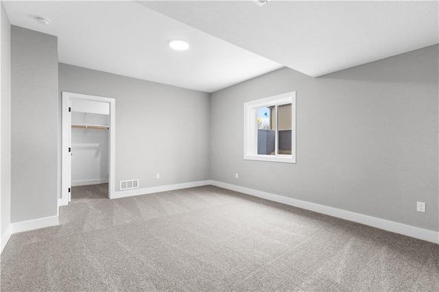 unfurnished bedroom featuring carpet flooring, a walk in closet, and a closet