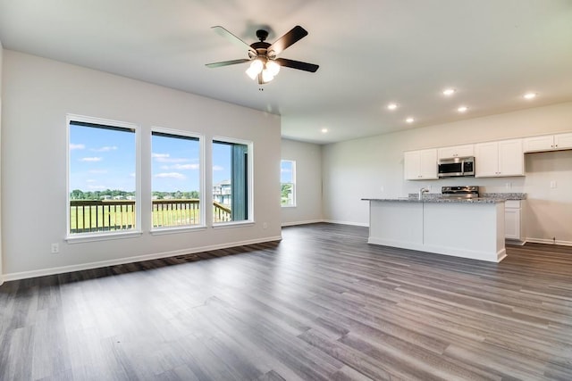 kitchen featuring light stone countertops, ceiling fan, dark wood-type flooring, stainless steel appliances, and white cabinets