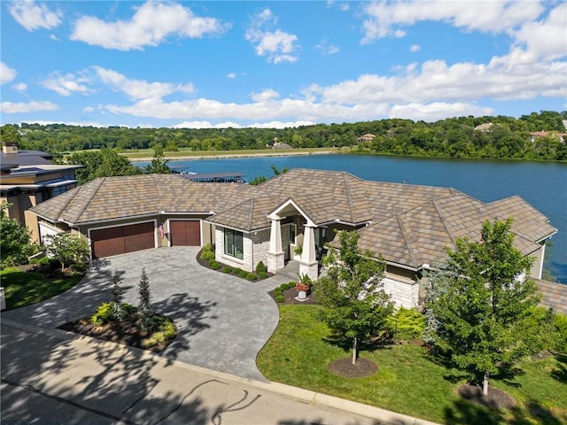 ranch-style house with a garage, a water view, and a front lawn