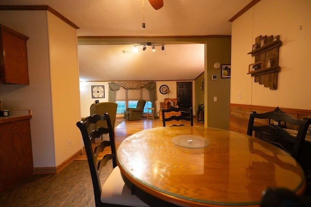 dining space with ceiling fan, crown molding, and wood walls