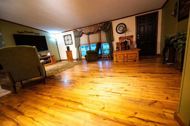 living room featuring light wood-type flooring, ornamental molding, and a textured ceiling