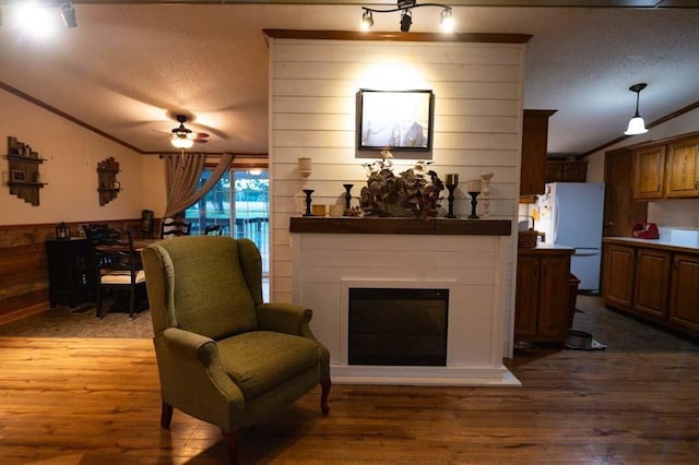 living room featuring vaulted ceiling, ornamental molding, and hardwood / wood-style flooring