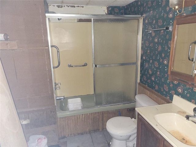 full bathroom with bath / shower combo with glass door, toilet, vanity, and tile patterned flooring