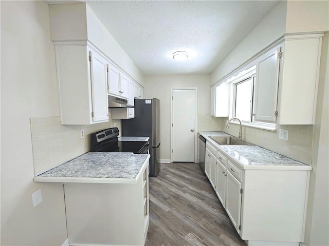 kitchen with hardwood / wood-style flooring, stainless steel appliances, sink, white cabinetry, and a textured ceiling