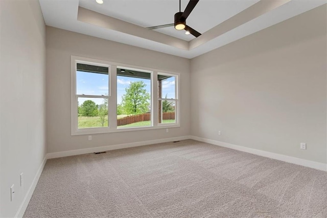 unfurnished room with carpet, ceiling fan, and a tray ceiling