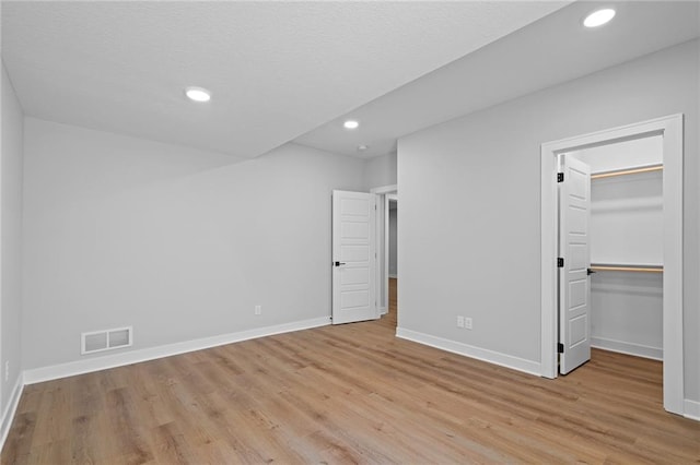 unfurnished bedroom featuring light hardwood / wood-style flooring, a walk in closet, and a closet