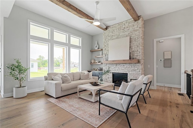 living room with a fireplace, beamed ceiling, light wood-type flooring, and ceiling fan