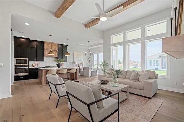 living room with ceiling fan with notable chandelier, light hardwood / wood-style flooring, and beam ceiling