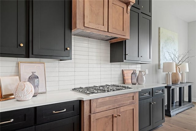 kitchen with light wood-type flooring, stainless steel gas cooktop, light brown cabinetry, and tasteful backsplash