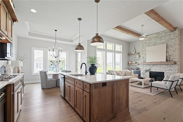 kitchen with appliances with stainless steel finishes, pendant lighting, a fireplace, sink, and a kitchen island with sink