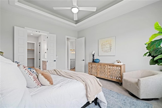 carpeted bedroom with ceiling fan and a raised ceiling