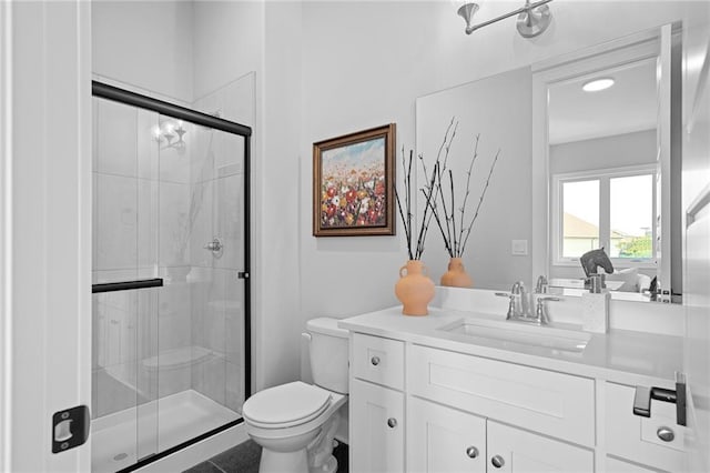 bathroom with vanity, a shower with door, and toilet