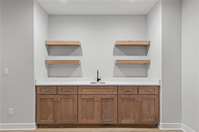 bar featuring light hardwood / wood-style flooring and sink