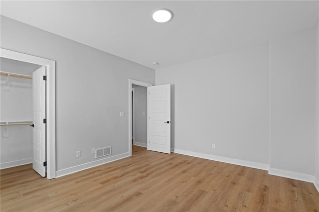 unfurnished bedroom featuring light wood-type flooring, a closet, and a spacious closet