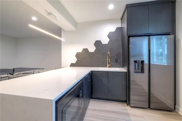 kitchen featuring sink, wine cooler, stainless steel fridge, backsplash, and kitchen peninsula