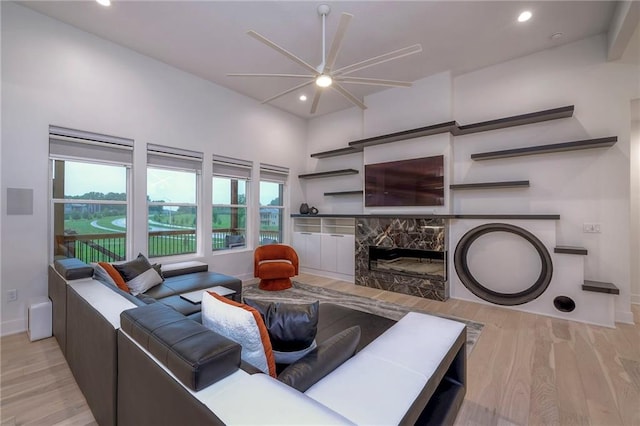 living room with a high end fireplace and light wood-type flooring