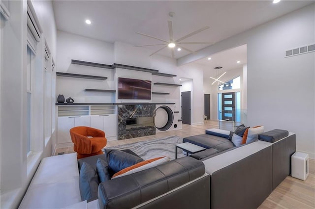 living room with a towering ceiling, a fireplace, and light wood-type flooring