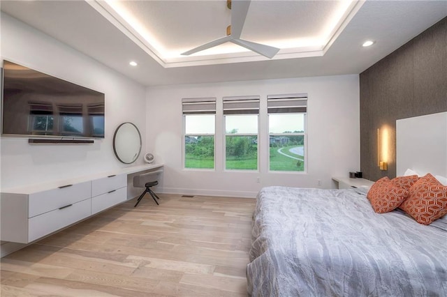 bedroom featuring a tray ceiling and light wood-type flooring