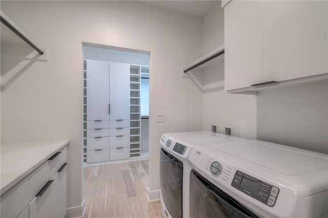 laundry room with separate washer and dryer, cabinets, and light wood-type flooring