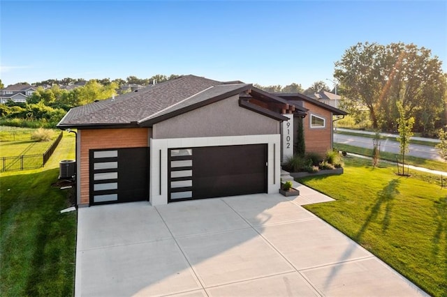 view of front of home with a garage, central AC, and a front yard