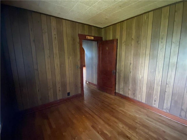 spare room featuring wooden walls and hardwood / wood-style flooring