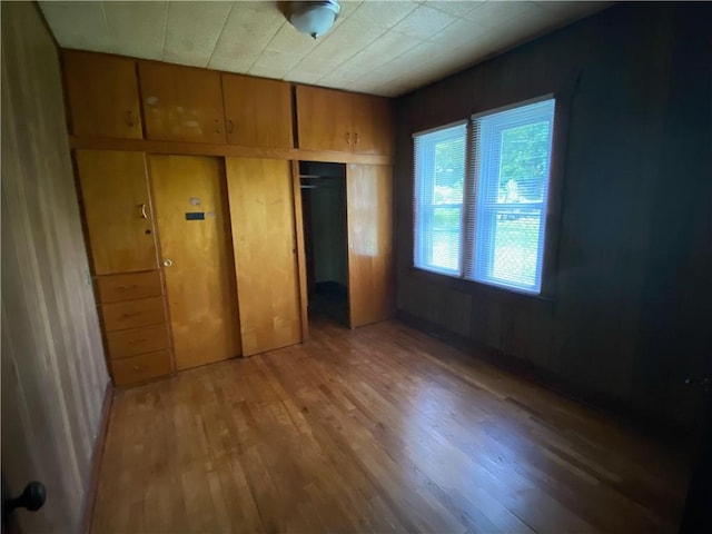 unfurnished bedroom with wood walls, a closet, and hardwood / wood-style floors