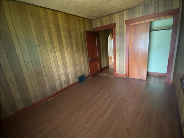 unfurnished bedroom with wood walls and a closet