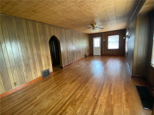 empty room with wood walls, hardwood / wood-style flooring, and ceiling fan