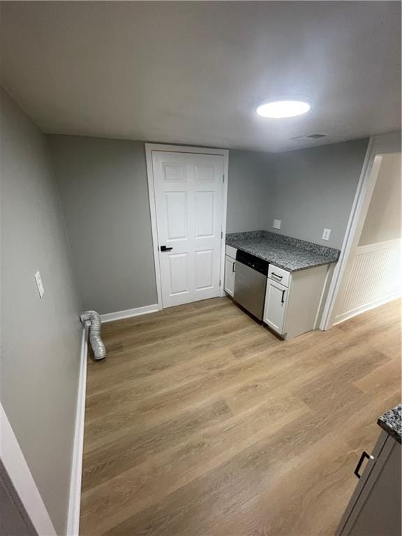 kitchen featuring light hardwood / wood-style floors, stainless steel dishwasher, and white cabinetry