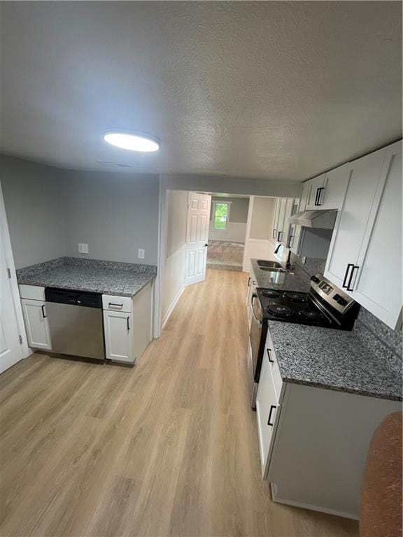 kitchen featuring white cabinetry, a textured ceiling, stainless steel appliances, and light hardwood / wood-style floors