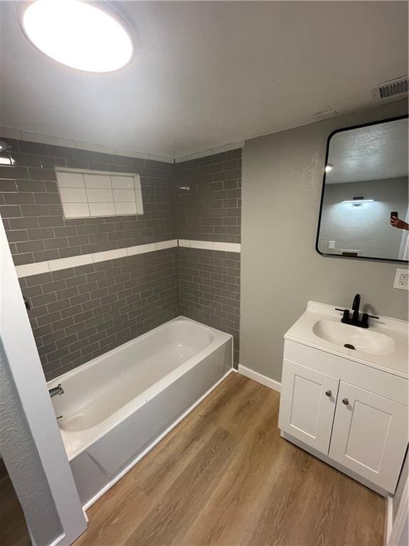 bathroom featuring tiled shower / bath, vanity, and wood-type flooring