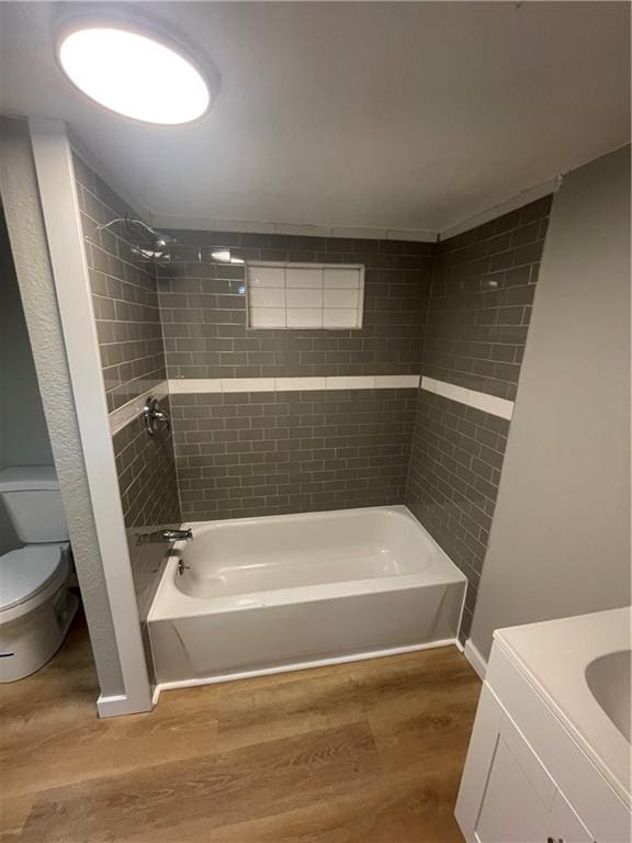 full bathroom with toilet, hardwood / wood-style floors, vanity, and tiled shower / bath combo