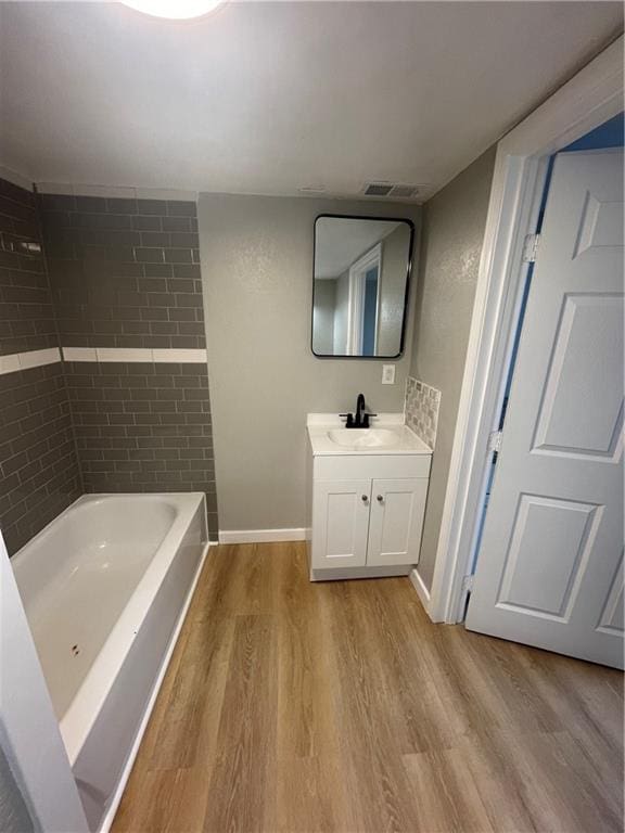 bathroom with vanity, a tub to relax in, and hardwood / wood-style floors