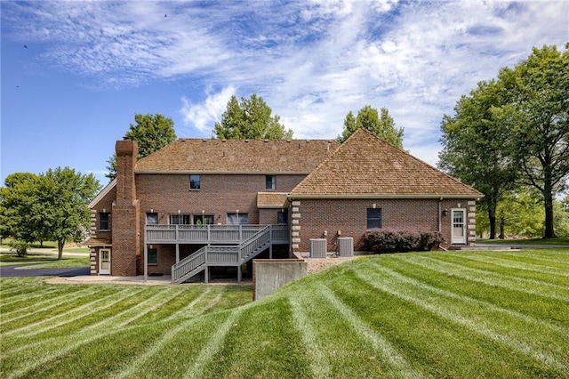 back of house featuring a deck, central AC unit, and a lawn