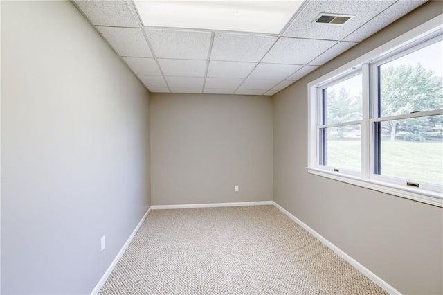 carpeted spare room with a drop ceiling