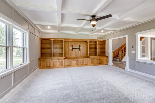 unfurnished living room with carpet, built in shelves, and a healthy amount of sunlight