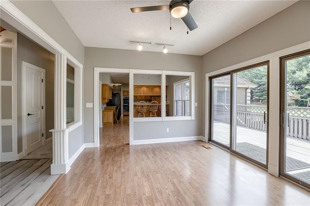 interior space featuring a textured ceiling, light wood-type flooring, and ceiling fan