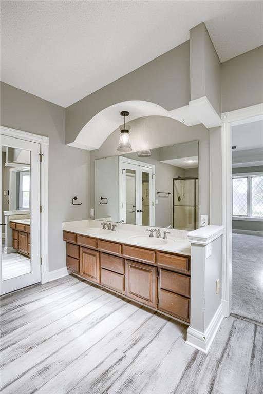 12815 NW 145th St, Platte City, MO 64079 - full bathroom with baseboards, a shower stall, a sink, double vanity, and wood finished floors