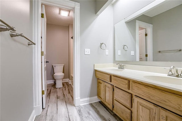 bathroom with vanity, wood-type flooring, a textured ceiling, and toilet