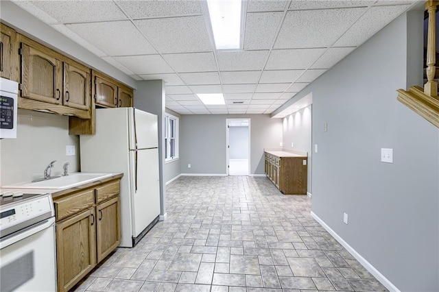 kitchen with a paneled ceiling, white appliances, and sink