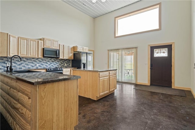 kitchen featuring sink, appliances with stainless steel finishes, backsplash, and a towering ceiling