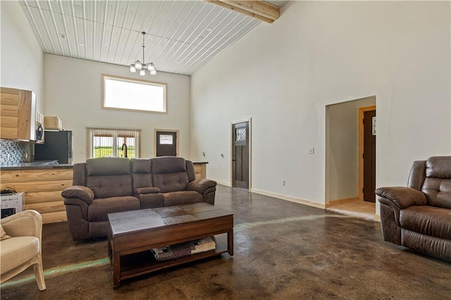 living room featuring beam ceiling, concrete flooring, a high ceiling, and an inviting chandelier