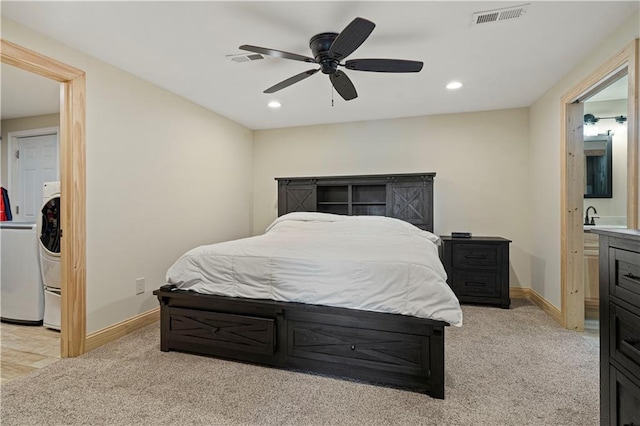 bedroom with washer / clothes dryer, light carpet, ensuite bathroom, and ceiling fan