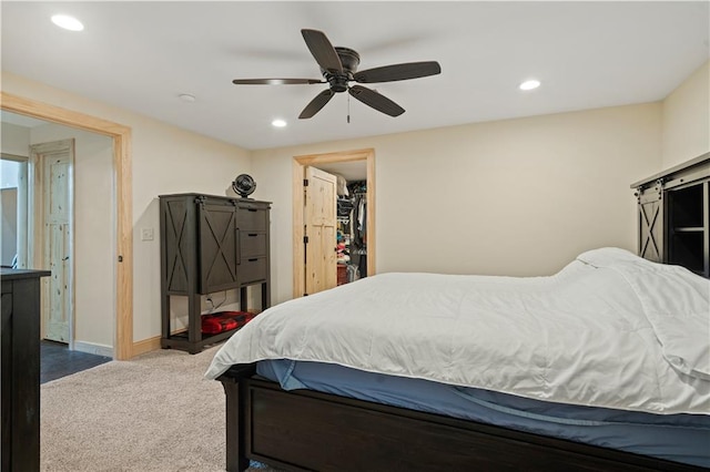 carpeted bedroom with a spacious closet, a closet, and ceiling fan