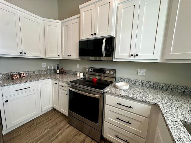 kitchen with stainless steel appliances, light stone countertops, white cabinets, and dark hardwood / wood-style flooring