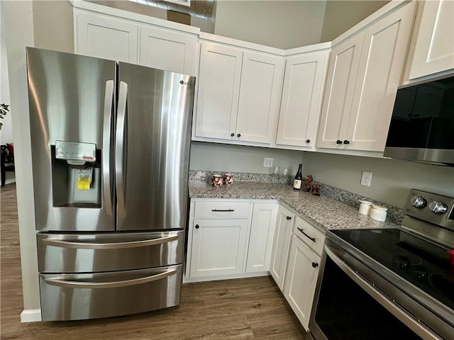 kitchen with light stone counters, stainless steel appliances, dark hardwood / wood-style floors, and white cabinets