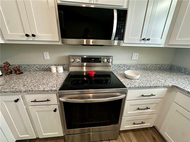 kitchen with stainless steel appliances, light stone countertops, and white cabinets