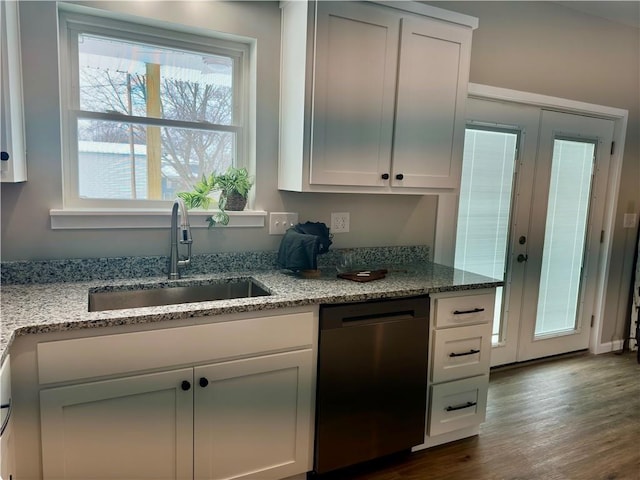 kitchen featuring dark wood-type flooring, sink, white cabinetry, stainless steel dishwasher, and light stone countertops